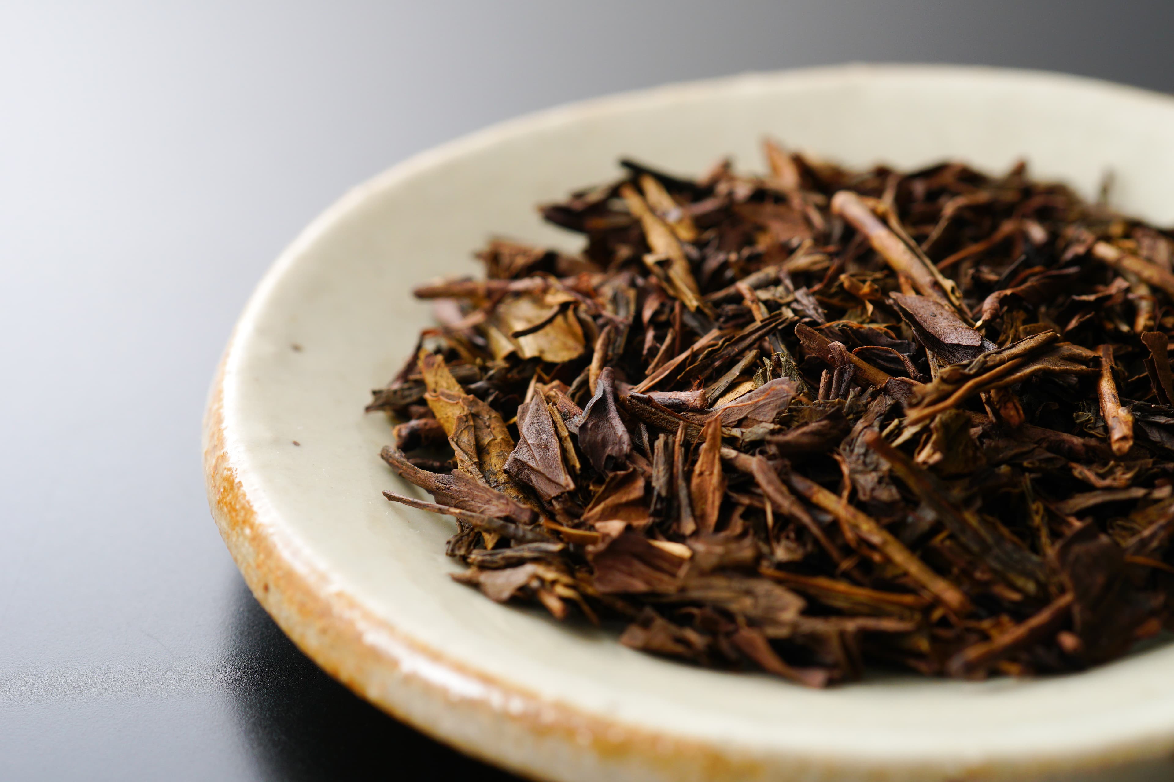 Roasted hojicha tea leaves on a ceramic plate